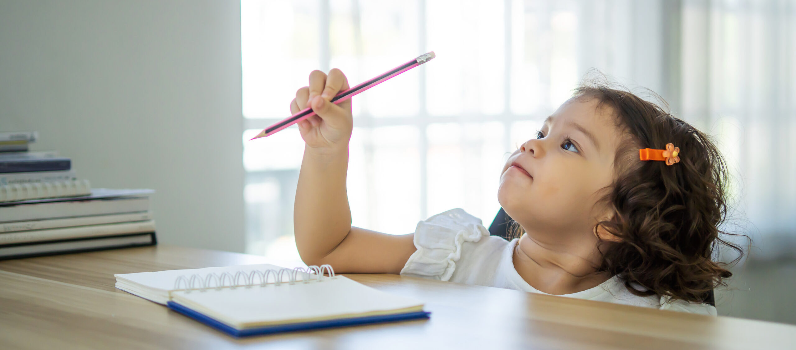 Cute little girl sit at desk at home doing homework, reading, wr